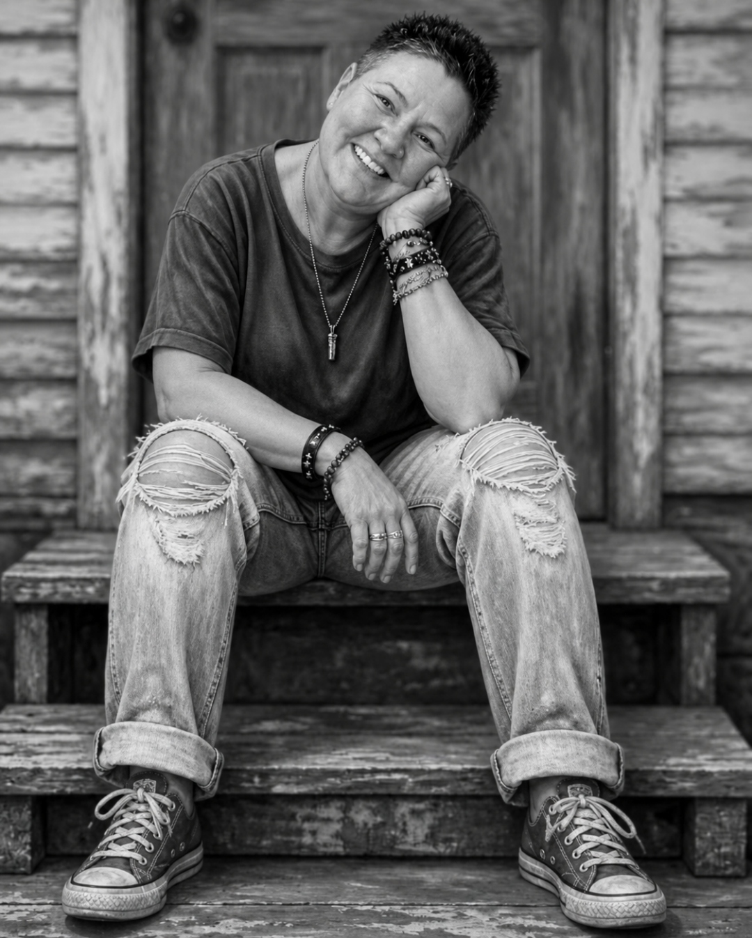 Jules Pollard sitting on wooden steps, smiling, resting her chin on her hand.